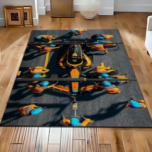 Könnte beinhalten: Rechteckiger Teppich mit einem futuristischen Fahrzeugdesign in Schwarz und Orange mit blauen Akzenten. Der Teppich hat einen grauen Hintergrund mit gelben Linien, die einer Landebahn ähneln. Das Design umfasst mehrere Propeller.