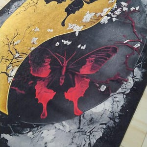 May include: A black and gold rug with a yin yang design featuring two butterflies. The butterfly on the gold side is black and the butterfly on the black side is red.