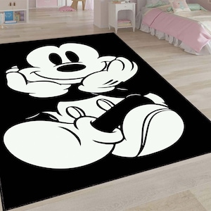 Puede incluir: Alfombra negra y blanca con una imagen de dibujos animados de Mickey Mouse sentado con las manos en el regazo.