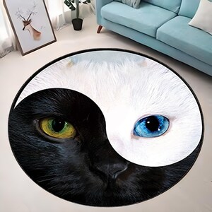 Könnte beinhalten: Ein runder Teppich mit einem Yin-Yang-Design, das eine schwarze Katze mit grünen Augen und eine weiße Katze mit blauen Augen zeigt.