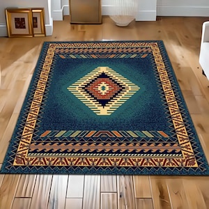 May include: A rectangular area rug with a central diamond pattern in cream, navy, and rust colors. The rug has a navy blue background with a patterned border in shades of gold, orange, and teal. The rug is placed on a hardwood floor.