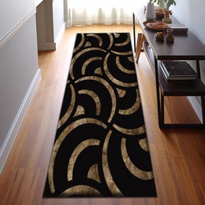 May include: Black and gold geometric runner rug with a pattern of overlapping circles. The rug has a modern design and would be a stylish addition to any home.