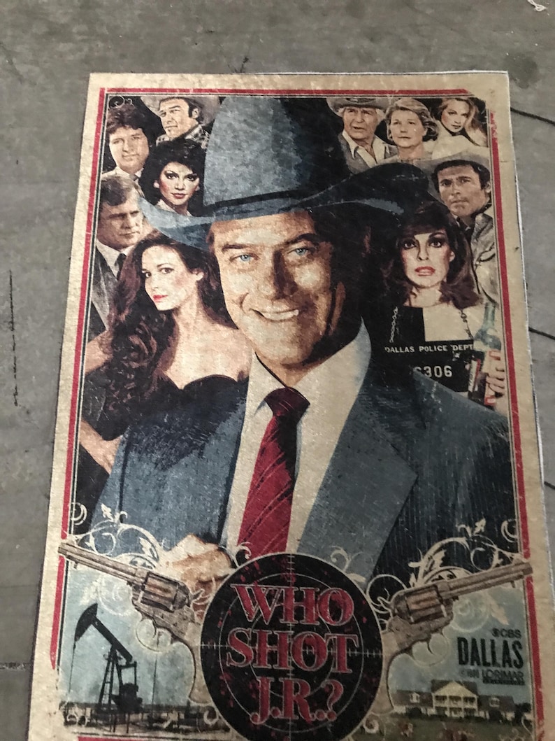 May include: A retro poster with a group of people, with a man in a hat and suit as the central figure. The poster includes the text "WHO SHOT J.R.?" and "DALLAS". The color scheme is muted with a distressed appearance.