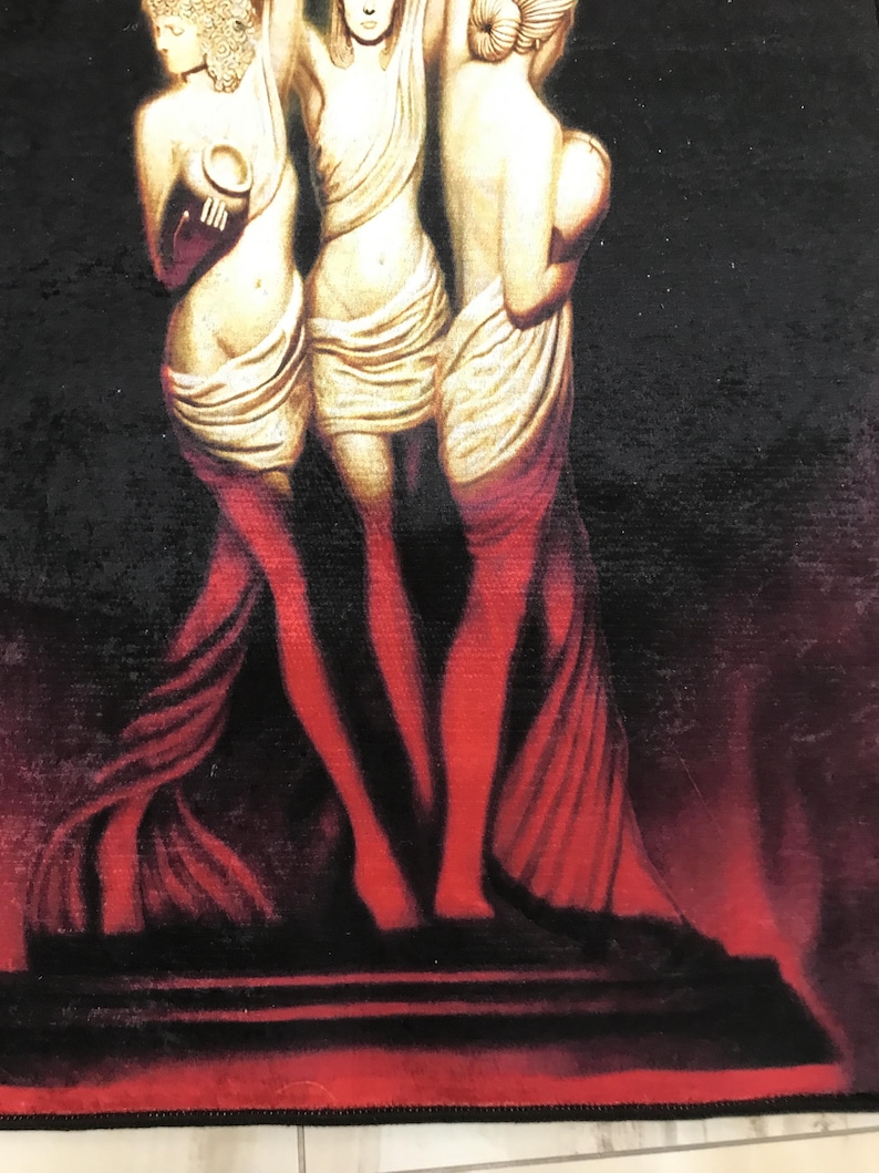 May include: Three golden statues of women standing on a red platform against a black background. The statues are wearing flowing robes and are holding up their arms.