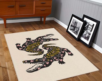 May include: A rectangular area rug with a cream-colored background featuring two black crocodiles positioned in a mirrored layout. The crocodiles are decorated with olive green leaf patterns along their backs and small pink hearts across their bodies.