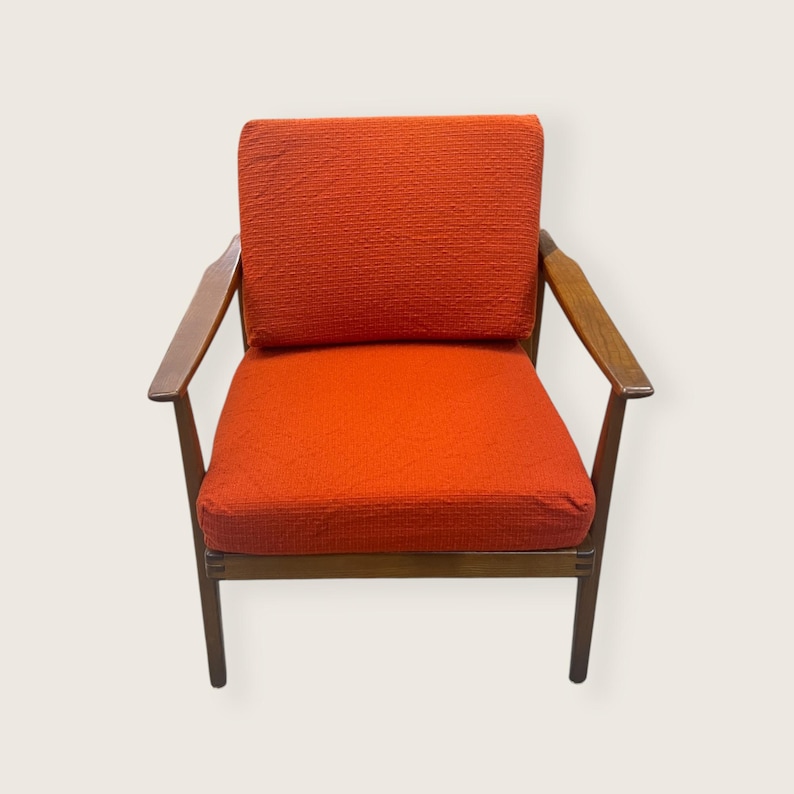 May include: Mid-century modern armchair with a vibrant orange textured fabric seat and back. The chair features a wooden frame and armrests, showcasing a classic design. The chair's dimensions are approximately 30 inches wide, 30 inches deep, and 30 inches high.