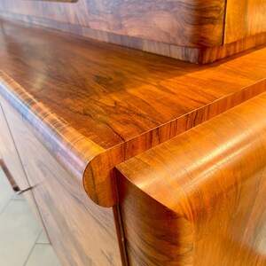 May include: A wooden cabinet with a curved edge and a wood grain pattern. The cabinet has a dark brown finish and is made of solid wood.