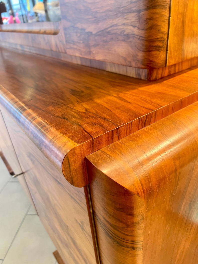 May include: A wooden cabinet with a curved edge and a wood grain pattern. The cabinet has a dark brown finish and is made of solid wood.