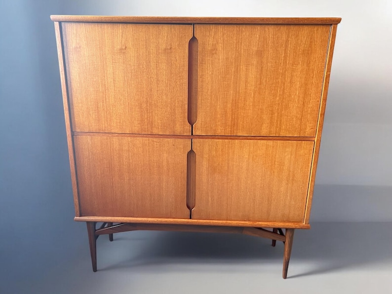 Puede incluir: Un aparador de madera de estilo moderno de mediados de siglo con cuatro puertas y un dise&ntilde;o sencillo. El aparador tiene un acabado de madera clara y se apoya en cuatro patas delgadas.