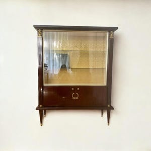 Vintage display cabinet in French Empire style. Art Déco display cabinet with brass ornamental elements on mahogany wood and brocade fabric.
