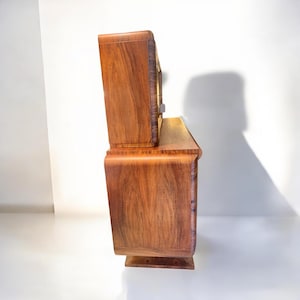 May include: A vintage wooden cabinet with a curved design and a glass-front top section. The cabinet is made of rich, dark wood with a natural grain pattern.