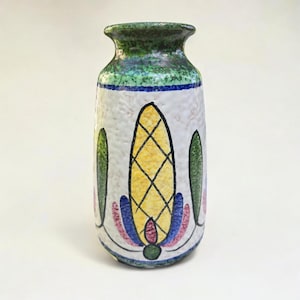 Könnte beinhalten: Eine Keramikvase mit strukturierter weißer Oberfläche, grünem Rand und Boden. Die Vase ist mit einem zentralen gelb-schwarzen Rautenmuster verziert, das von grünen und rosa blattartigen Motiven und blauen Akzenten flankiert wird.