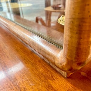 May include: Close-up of the top edge of a wooden cabinet with a glass display case. The cabinet has a rich brown wood finish and the glass is clear. The wood has a natural grain pattern.