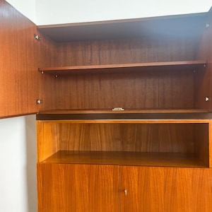 Puede incluir: Un mueble de madera de estilo moderno de mediados de siglo, con estanter&iacute;as abiertas y una secci&oacute;n de armario cerrada. La madera tiene un tono c&aacute;lido y veta visible. Las puertas est&aacute;n abiertas, mostrando los estantes interiores. Dise&ntilde;o sencillo y limpio.