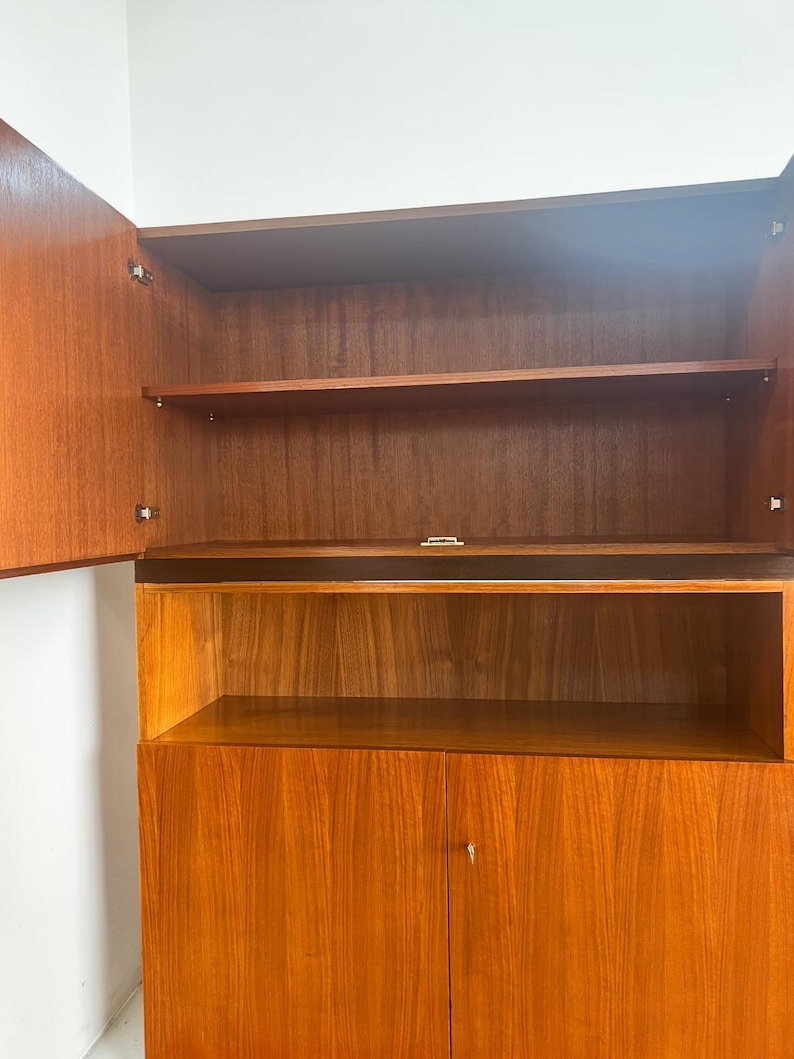 Puede incluir: Un mueble de madera de estilo moderno de mediados de siglo, con estanter&iacute;as abiertas y una secci&oacute;n de armario cerrada. La madera tiene un tono c&aacute;lido y veta visible. Las puertas est&aacute;n abiertas, mostrando los estantes interiores. Dise&ntilde;o sencillo y limpio.