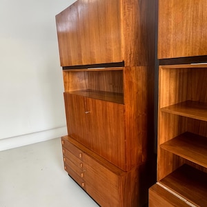 Puede incluir: Un mueble de madera de estilo moderno de mediados de siglo con un acabado marr&oacute;n c&aacute;lido. El mueble presenta una combinaci&oacute;n de cajones, estantes y almacenamiento cerrado. El dise&ntilde;o incluye una base negra y detalles horizontales negros.