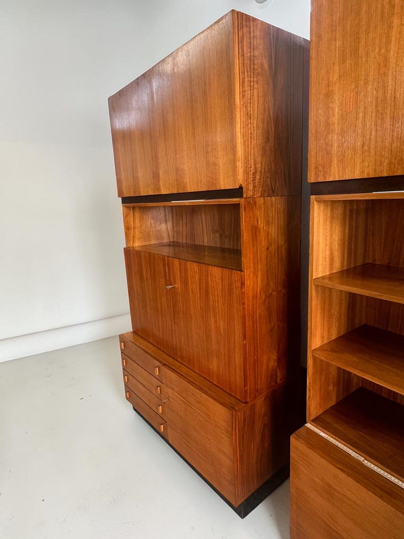 Puede incluir: Un mueble de madera de estilo moderno de mediados de siglo con un acabado marr&oacute;n c&aacute;lido. El mueble presenta una combinaci&oacute;n de cajones, estantes y almacenamiento cerrado. El dise&ntilde;o incluye una base negra y detalles horizontales negros.