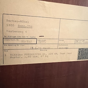 Puede incluir: Un primer plano de una factura de papel para una vitrina Fredericia 41 de 124 cm de teca. La factura indica que el art&iacute;culo mide 0,8 metros c&uacute;bicos y pesa 67 kg.
