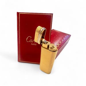 Original vintage Cartier lighter, gold-plated with a Trinity band, made in 1983, with a certificate, original box, and travel case.