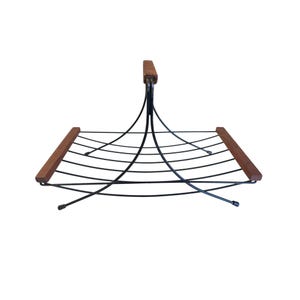 May include: A mid-century modern magazine rack. The rack features a black metal frame with curved wire supports and wooden accents. The handle and end pieces are made of wood. The design is minimalist and functional, suitable for home decor.