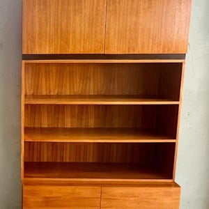Puede incluir: Un mueble de madera de estilo moderno de mediados de siglo con un acabado marr&oacute;n claro. El mueble tiene dos puertas superiores, estanter&iacute;as abiertas y puertas inferiores. El mueble mide aproximadamente 183 cm de alto y 91 cm de ancho.
