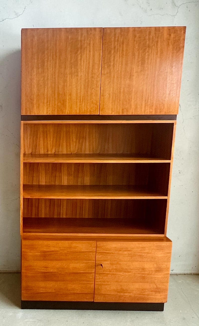 Puede incluir: Un mueble de madera de estilo moderno de mediados de siglo con un acabado marr&oacute;n claro. El mueble tiene dos puertas superiores, estanter&iacute;as abiertas y puertas inferiores. El mueble mide aproximadamente 183 cm de alto y 91 cm de ancho.