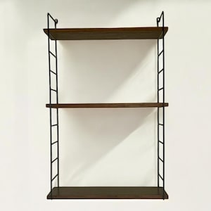 May include: A three-tiered wall shelf featuring dark brown wooden shelves and a black metal frame. The rectangular shelves are supported by a ladder-style frame. This shelf is designed for storage and display purposes.