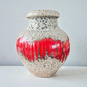 Könnte beinhalten: Eine Vintage-Keramikvase mit einer strukturierten, gesprenkelten grau-beigen Oberfläche. Ein kräftiges, horizontales Band aus leuchtend roten, vertikalen Strichen umgibt die Vase. Die Vase hat einen abgerundeten Körper und einen leicht ausgestellten Rand, der ein modernes Design aus der Mitte des Jahrhunderts zeigt.