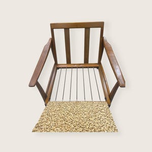 May include: A vintage wooden armchair with a light brown frame and armrests. The seat features a patterned fabric in shades of beige and brown. The backrest has vertical wooden slats. The chair's design is mid-century modern.