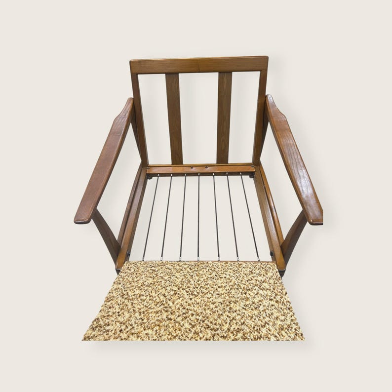 May include: A vintage wooden armchair with a light brown frame and armrests. The seat features a patterned fabric in shades of beige and brown. The backrest has vertical wooden slats. The chair's design is mid-century modern.