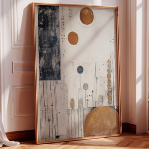 Op de afbeelding: Abstracte kunstprint in een gouden lijst. Het kunstwerk heeft een crèmekleurige achtergrond met donkerblauwe en bruine vormen, waaronder een grote rechthoek, cirkels en een halve cirkel. Dunne zwarte lijnen en kleine stippen voegen details toe.