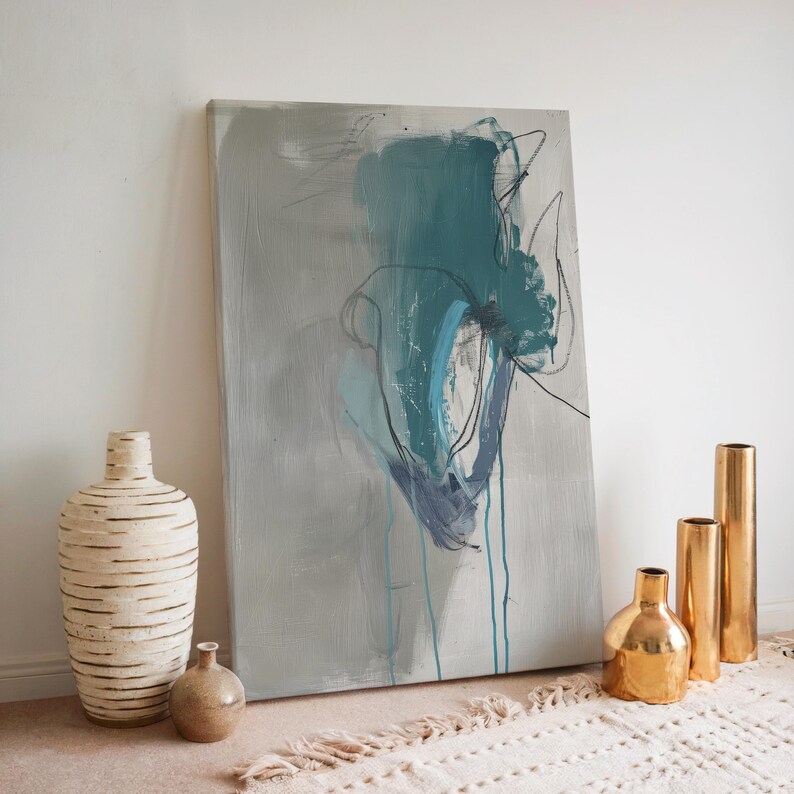 May include: Abstract art canvas with teal and blue brushstrokes on a gray background. Decorative vases in various sizes and finishes, including a tall, textured white vase, a small brown vase, and gold metallic vases, are arranged in front of the artwork.