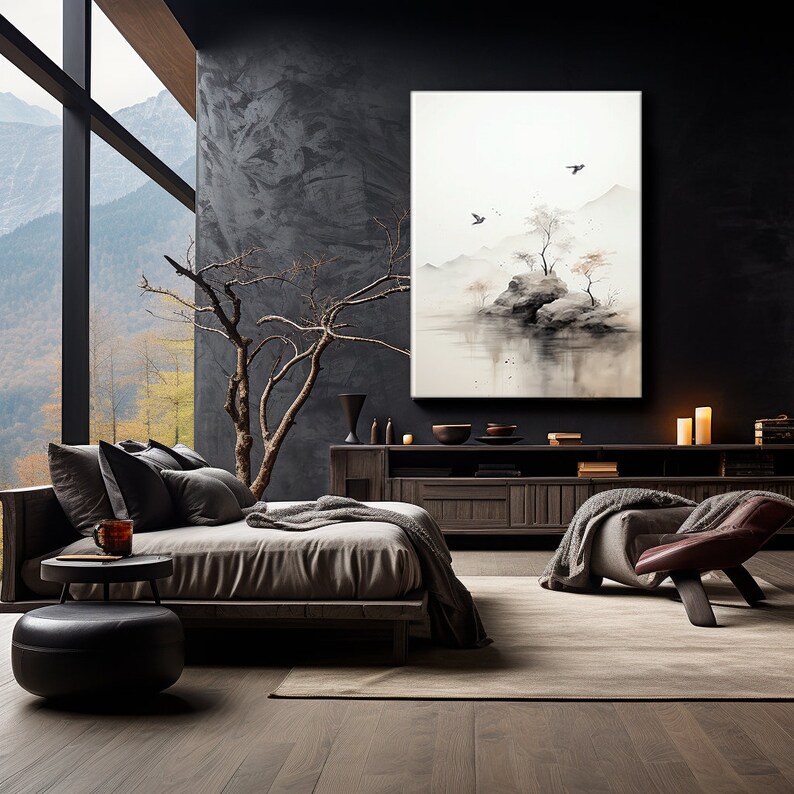 May include: A minimalist bedroom interior with a dark grey wall, a large window with a view of a mountain range, a bed with a grey headboard and a grey blanket, a dark wood side table with a small round stool, a dark wood cabinet with a painting of a misty landscape with a small island and birds, and a brown leather armchair with a grey throw blanket.
