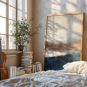 May include: A cello leans against a window with sunlight streaming through. A large framed abstract painting rests against the wall near a bed with white linens. A potted plant and stacked books are also visible.