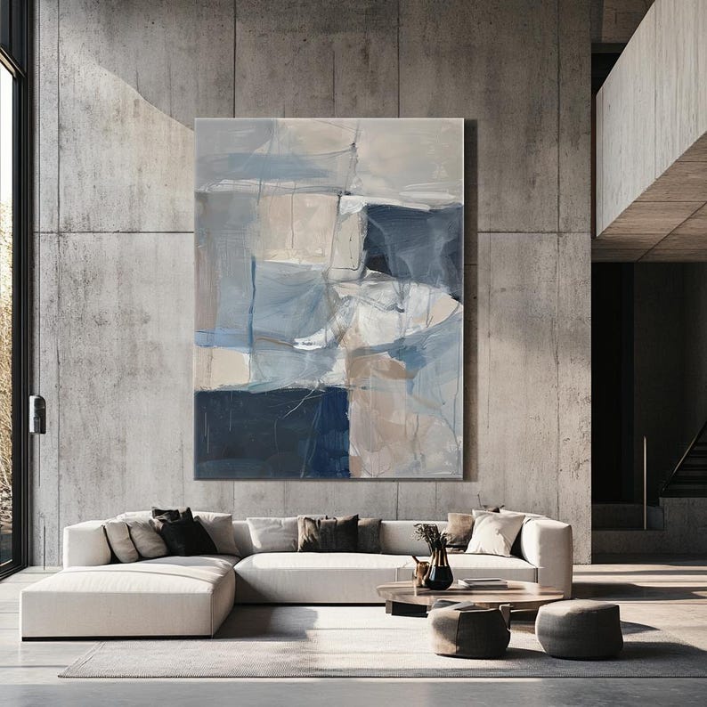 Puede incluir: Pintura abstracta con tonos de azul, blanco y beige. La pintura est&aacute; colgada en una pared de hormig&oacute;n en un sal&oacute;n moderno.