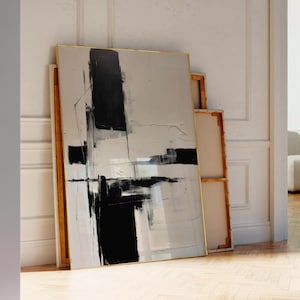 以下が含まれることがあります： 黒、白、グレーのトーンの抽象画。絵画は金色の額縁に収められ、白い壁に立てかけられています。