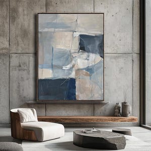 Puede incluir: Pintura abstracta de estilo moderno con tonos de azul, beige y blanco. La pintura est&aacute; enmarcada y colgada en una pared de hormig&oacute;n gris.