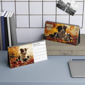 May include: A spiral-bound desk calendar featuring a Border Collie theme with autumn leaf imagery. The front page displays a large adult dog and two puppies in fall foliage, with the text 'August 2027' and a monthly grid visible on the left.