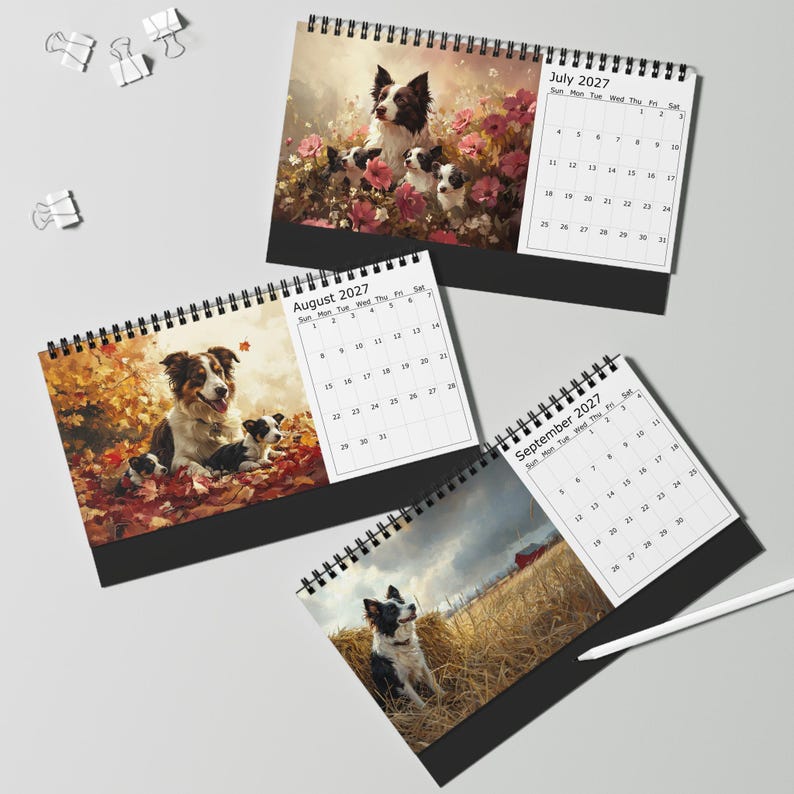 May include: Three spiral-bound 2027 desk calendars featuring dog illustrations. July shows a border collie with puppies in pink flowers. August displays a dog with puppies in autumn leaves. September features a dog in a field with a red barn.