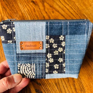 Op de afbeelding: Een blauwe denim patchwork-tas met rits en een bruin lederen label met de tekst "Handmade".