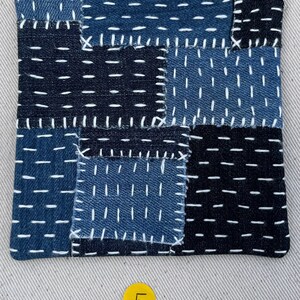 May include: A blue and black patchwork fabric square with white stitching. The fabric is made of denim and has a variety of textures. The square is labelled with the number "5".