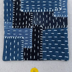 May include: A blue and black patchwork square made of denim fabric with white stitching. The square is numbered "4" in yellow.