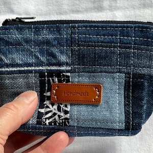 Może przedstawiać: Mała niebieska saszetka z denimu w patchworku z zamkiem błyskawicznym i brązową skórzaną metką z napisem "Handmade".