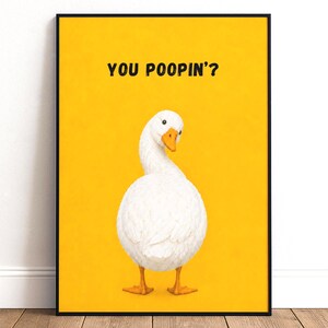 Könnte beinhalten: Ein gerahmter Wandkunstdruck mit einer weißen Gans mit orangefarbenem Schnabel vor einem einfarbigen gelben Hintergrund. Der Text YOU POOPIN'? steht in schwarzen Großbuchstaben über der Gans, die über ihre Schulter zurückblickt.
