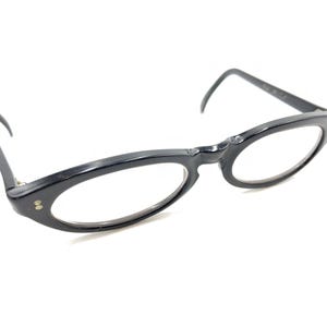 May include: Black plastic framed spectacles with oval lenses.