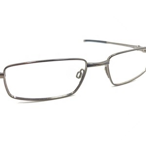 May include: Silver-toned metal eyeglasses with a rectangular frame.