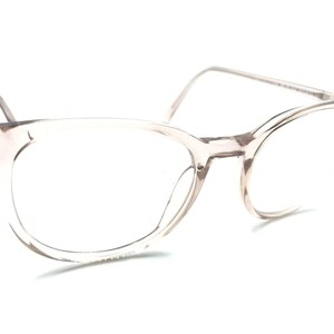 May include: Clear, translucent eyeglasses with a rounded, rectangular frame. The frame is a light brown color.
