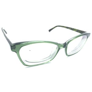 May include: A pair of eyeglasses with a translucent olive green frame in a cat-eye shape. The temples feature a dark green and brown tortoiseshell pattern. The clear lenses are set within the plastic frame, which has a smooth, glossy finish.