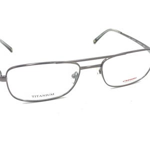 Puede incluir: Gafas de aviador de titanio plateadas con lentes transparentes. El nombre de la marca "CERRUTI 1881" está impreso en rojo en la lente derecha.