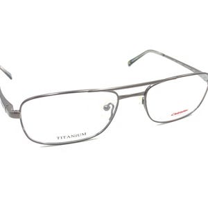 May include: Silver titanium aviator style eyeglasses with clear lenses. The frame has the word "TITANIUM" printed on the inside of the right lens.